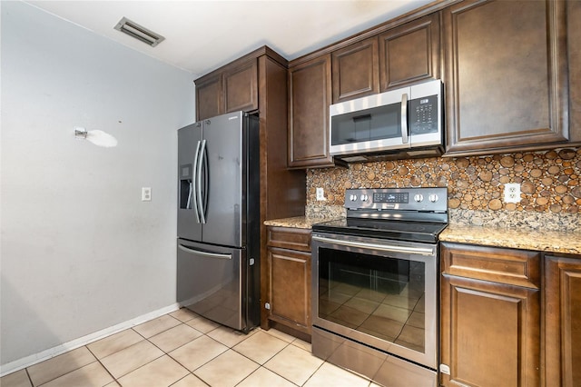 kitchen with light stone counters, light tile patterned flooring, appliances with stainless steel finishes, and tasteful backsplash