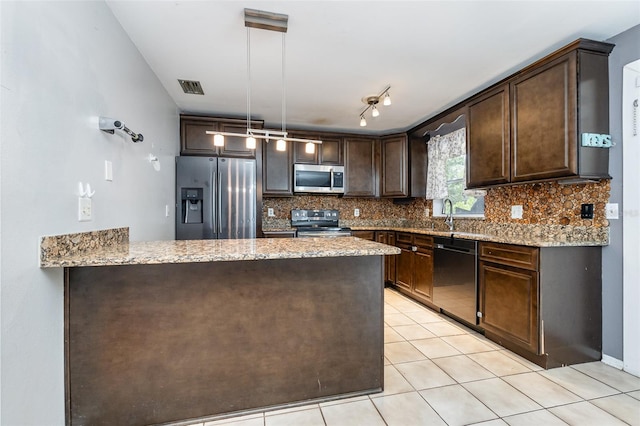 kitchen featuring light stone counters, light tile patterned floors, dark brown cabinets, decorative light fixtures, and appliances with stainless steel finishes