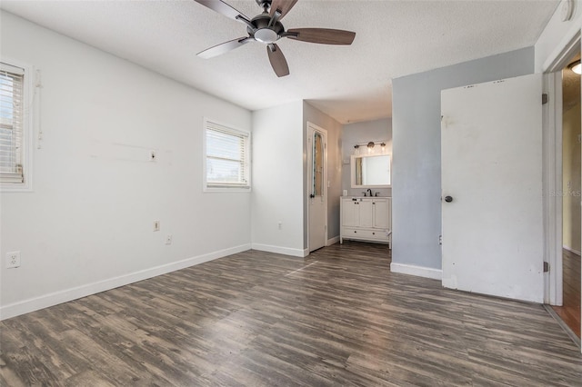 unfurnished bedroom with a textured ceiling, connected bathroom, ceiling fan, and dark wood-type flooring