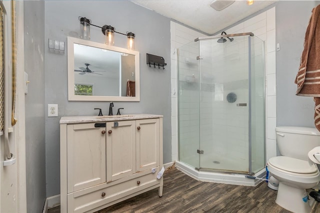 bathroom with ceiling fan, vanity, an enclosed shower, wood-type flooring, and toilet