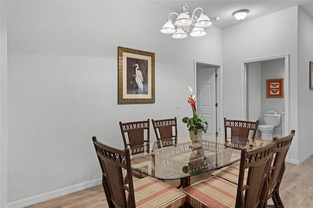 dining space with a textured ceiling, an inviting chandelier, and light hardwood / wood-style flooring