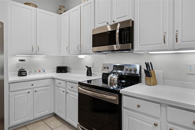 kitchen with appliances with stainless steel finishes, white cabinetry, and light tile patterned floors