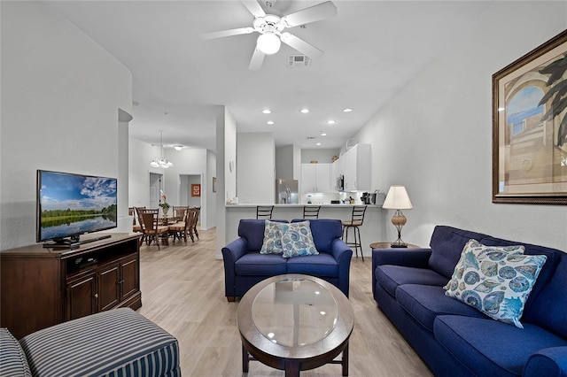 living room with light hardwood / wood-style flooring and ceiling fan with notable chandelier