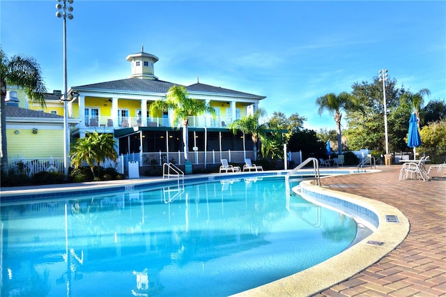 view of pool with a sunroom and a patio