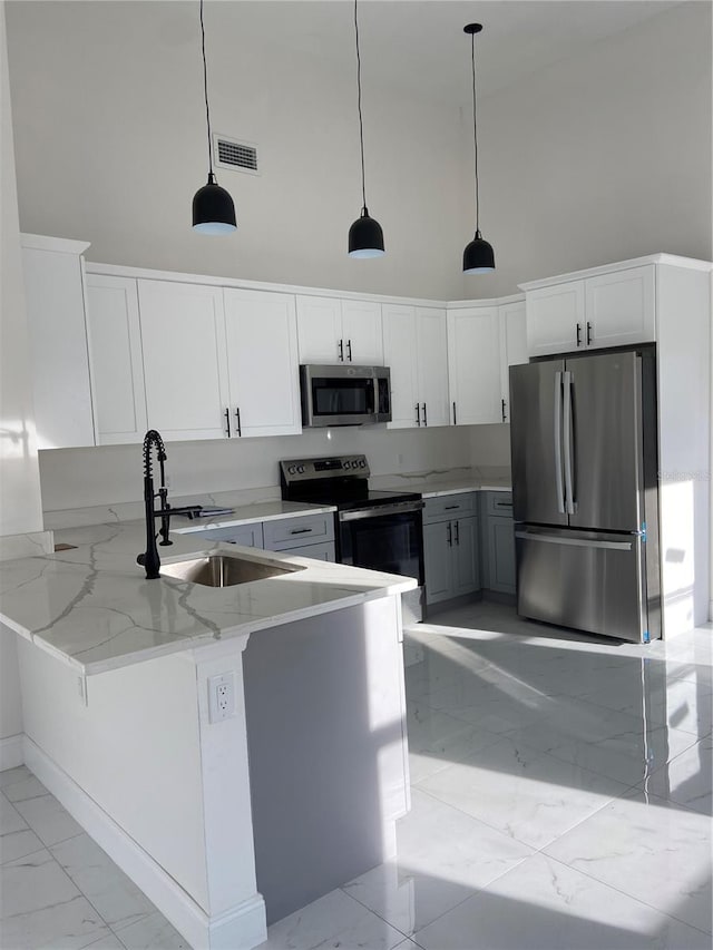 kitchen featuring decorative light fixtures, white cabinets, and appliances with stainless steel finishes