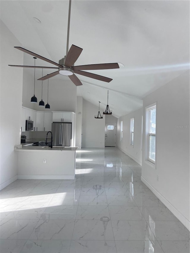 unfurnished living room featuring sink, high vaulted ceiling, and ceiling fan