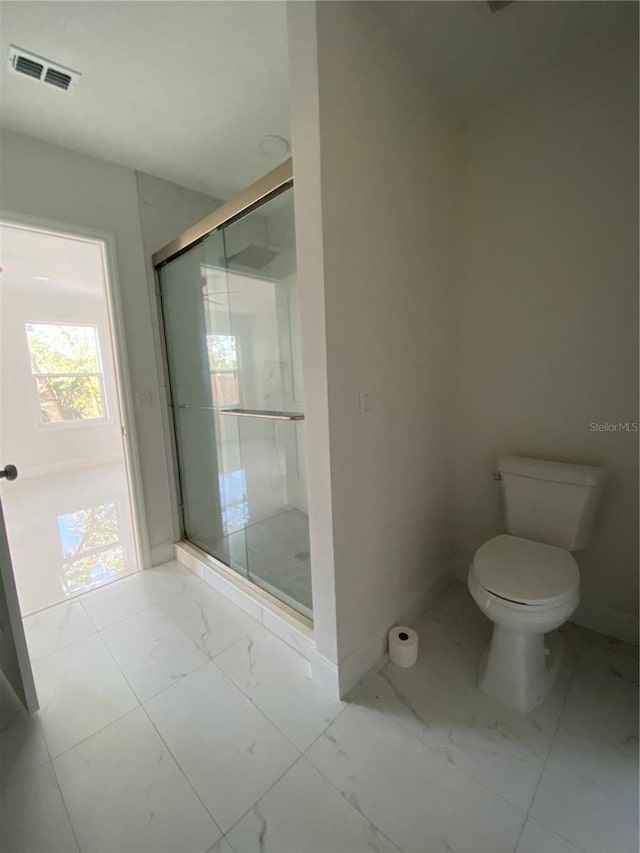 bathroom featuring toilet and a shower with door