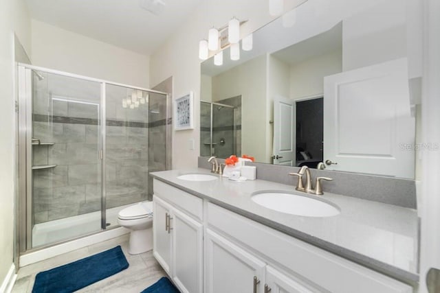 full bathroom with double vanity, a stall shower, toilet, and a sink