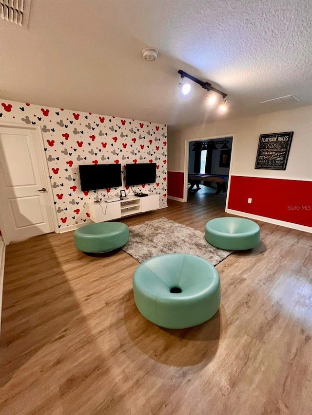 playroom featuring wood finished floors, baseboards, and a textured ceiling