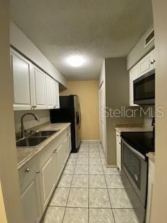 kitchen featuring white cabinetry, appliances with stainless steel finishes, sink, and light tile patterned floors