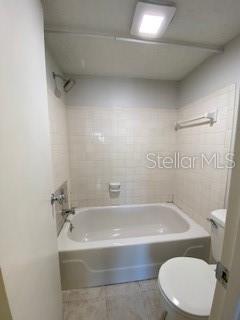 bathroom featuring shower / tub combination, tile patterned floors, and toilet