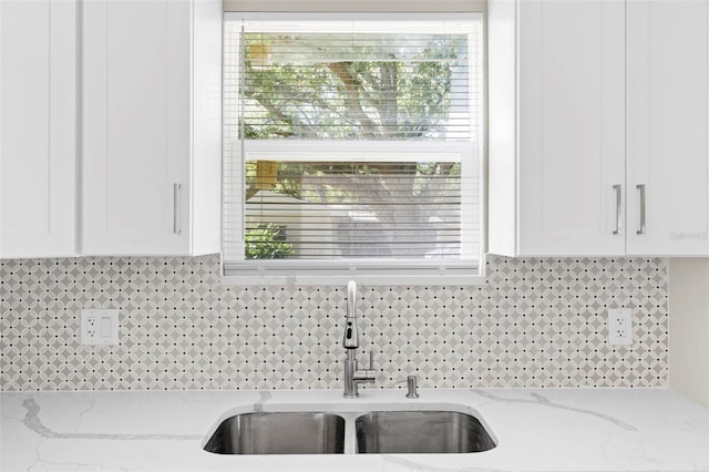 details with light stone counters, white cabinetry, tasteful backsplash, and sink