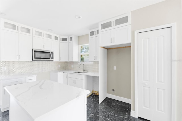 kitchen with white cabinets, light stone countertops, sink, and a center island