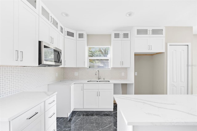 kitchen with white cabinets, light stone counters, tasteful backsplash, and sink