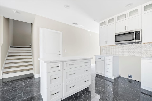 kitchen with white cabinets, a kitchen island, and decorative backsplash