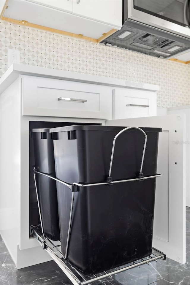 interior details featuring white cabinetry, refrigerator, tasteful backsplash, and ventilation hood