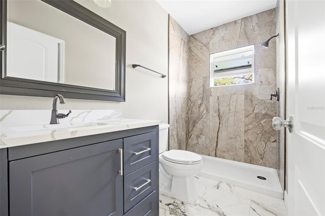 bathroom with a tile shower, vanity, and toilet