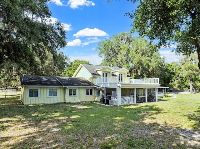 rear view of house featuring a yard and a sunroom