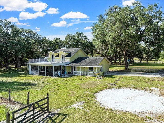 4350 E Hinson Ave, Haines City, FL 33844 - rear view of house with covered porch, driveway, a balcony, a sunroom, and view of scattered trees