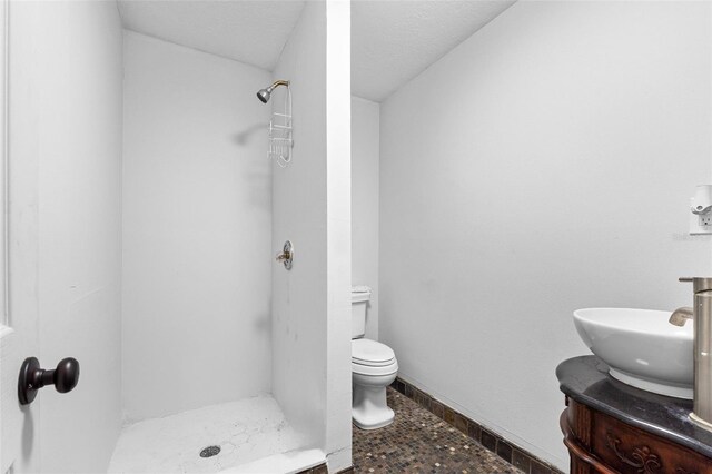 bathroom with a textured ceiling, a shower, vanity, and toilet