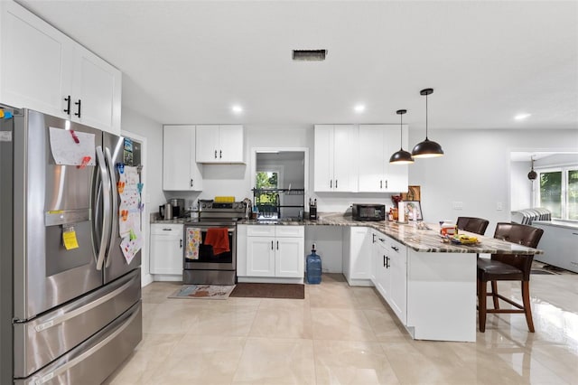 kitchen featuring decorative light fixtures, white cabinetry, stainless steel appliances, a breakfast bar, and dark stone countertops