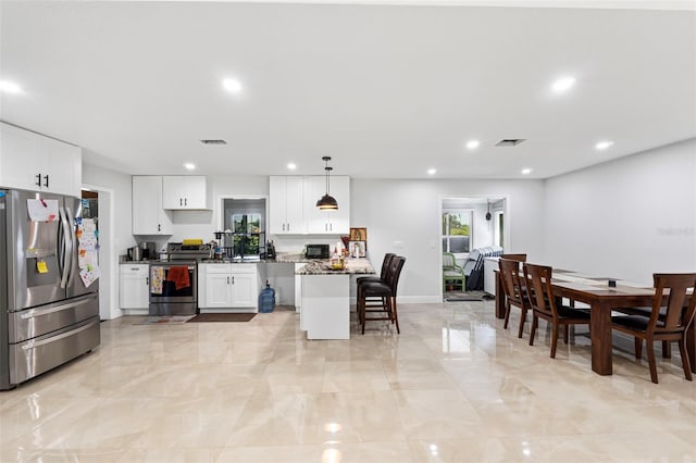 kitchen featuring dark stone countertops, pendant lighting, appliances with stainless steel finishes, and white cabinetry