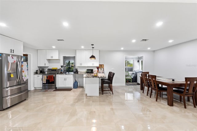 4350 E Hinson Ave, Haines City, FL 33844 - kitchen with appliances with stainless steel finishes, a kitchen bar, white cabinets, recessed lighting, and light marble finish floors