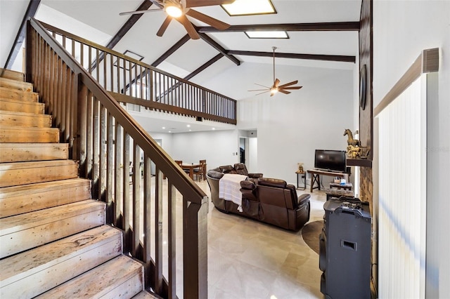 staircase with beamed ceiling, ceiling fan, and high vaulted ceiling