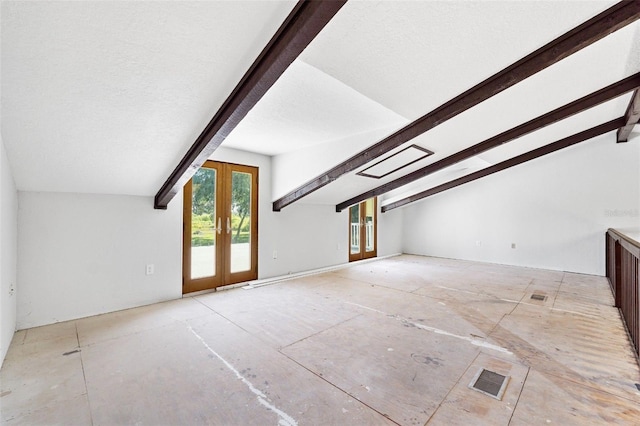 additional living space with lofted ceiling with beams, a textured ceiling, and french doors