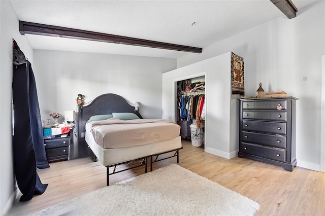 bedroom with beam ceiling, a closet, and light hardwood / wood-style floors