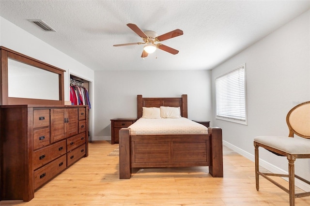 bedroom with a textured ceiling, light hardwood / wood-style floors, ceiling fan, and a closet