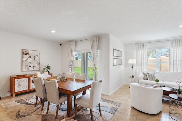 dining area with a textured ceiling, light tile patterned flooring, and a wealth of natural light