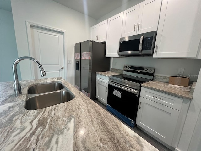 kitchen featuring light stone counters, stainless steel appliances, sink, and white cabinetry