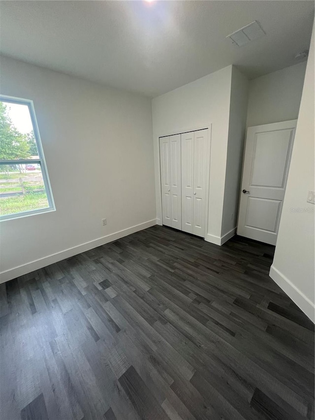 unfurnished bedroom featuring a closet and dark wood-type flooring