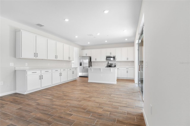 kitchen with stainless steel appliances, a kitchen breakfast bar, a center island, and white cabinets