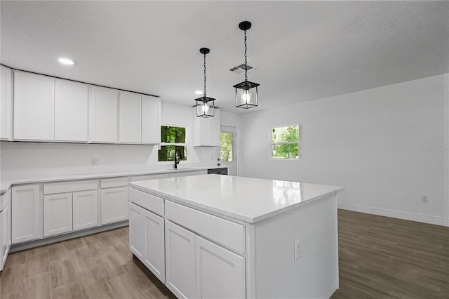 kitchen featuring a kitchen island, light wood-type flooring, white cabinetry, and sink