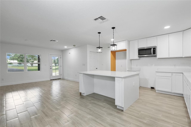 kitchen featuring light hardwood / wood-style floors, hanging light fixtures, white cabinetry, and a center island