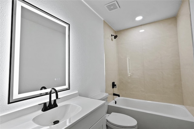 full bathroom featuring tiled shower / bath combo, vanity, and toilet