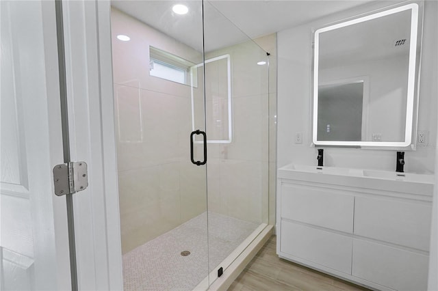 bathroom featuring walk in shower, vanity, and hardwood / wood-style flooring