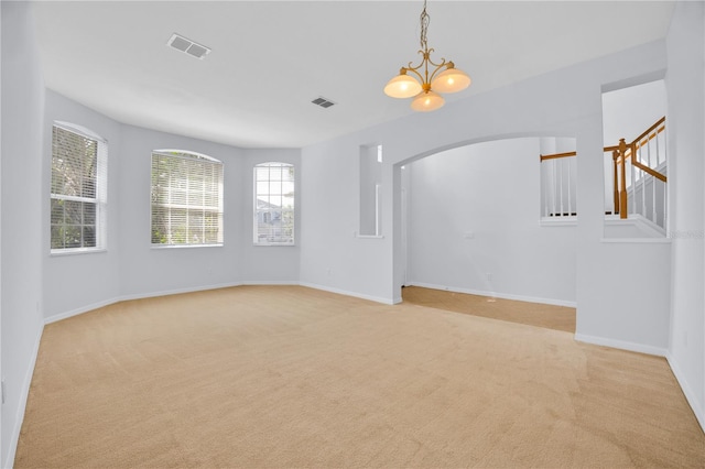 unfurnished room with light carpet and a notable chandelier