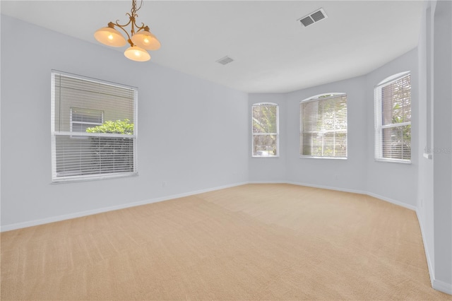 unfurnished room with light colored carpet and a chandelier