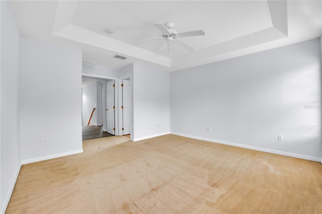 carpeted spare room featuring ceiling fan and a tray ceiling