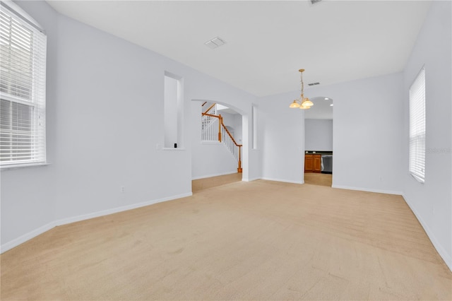 carpeted empty room featuring an inviting chandelier and a healthy amount of sunlight