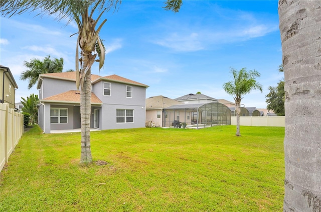 back of property featuring glass enclosure and a lawn