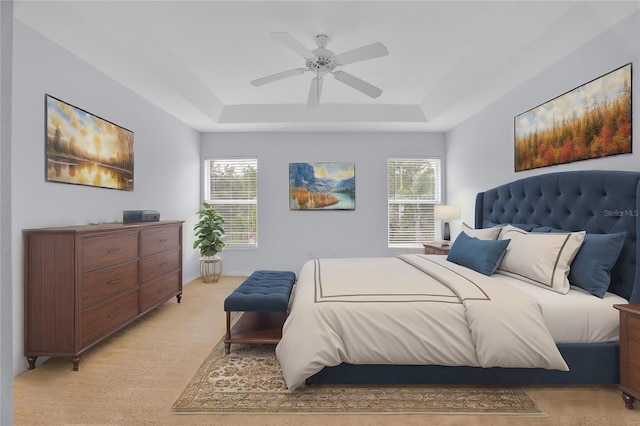 carpeted bedroom featuring ceiling fan and a raised ceiling