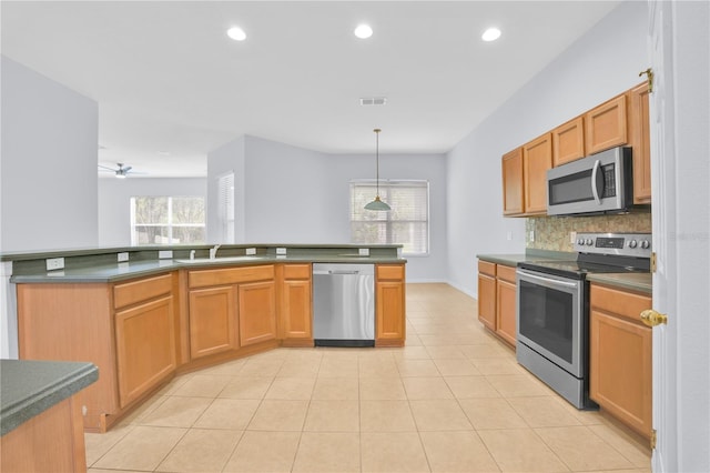 kitchen with appliances with stainless steel finishes, decorative backsplash, decorative light fixtures, light tile patterned flooring, and sink