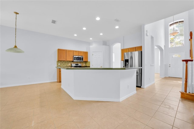 kitchen featuring decorative light fixtures, light tile patterned floors, appliances with stainless steel finishes, and a center island