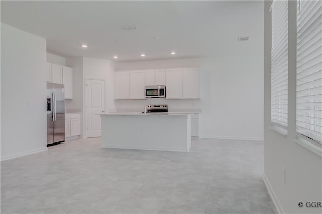 kitchen with appliances with stainless steel finishes, a center island with sink, and white cabinetry