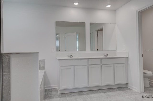 bathroom with tile patterned flooring, a bath, vanity, and toilet