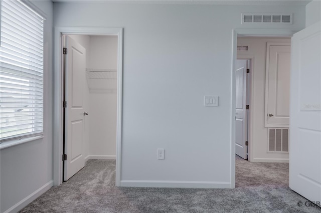 unfurnished bedroom featuring light carpet, a closet, and a spacious closet